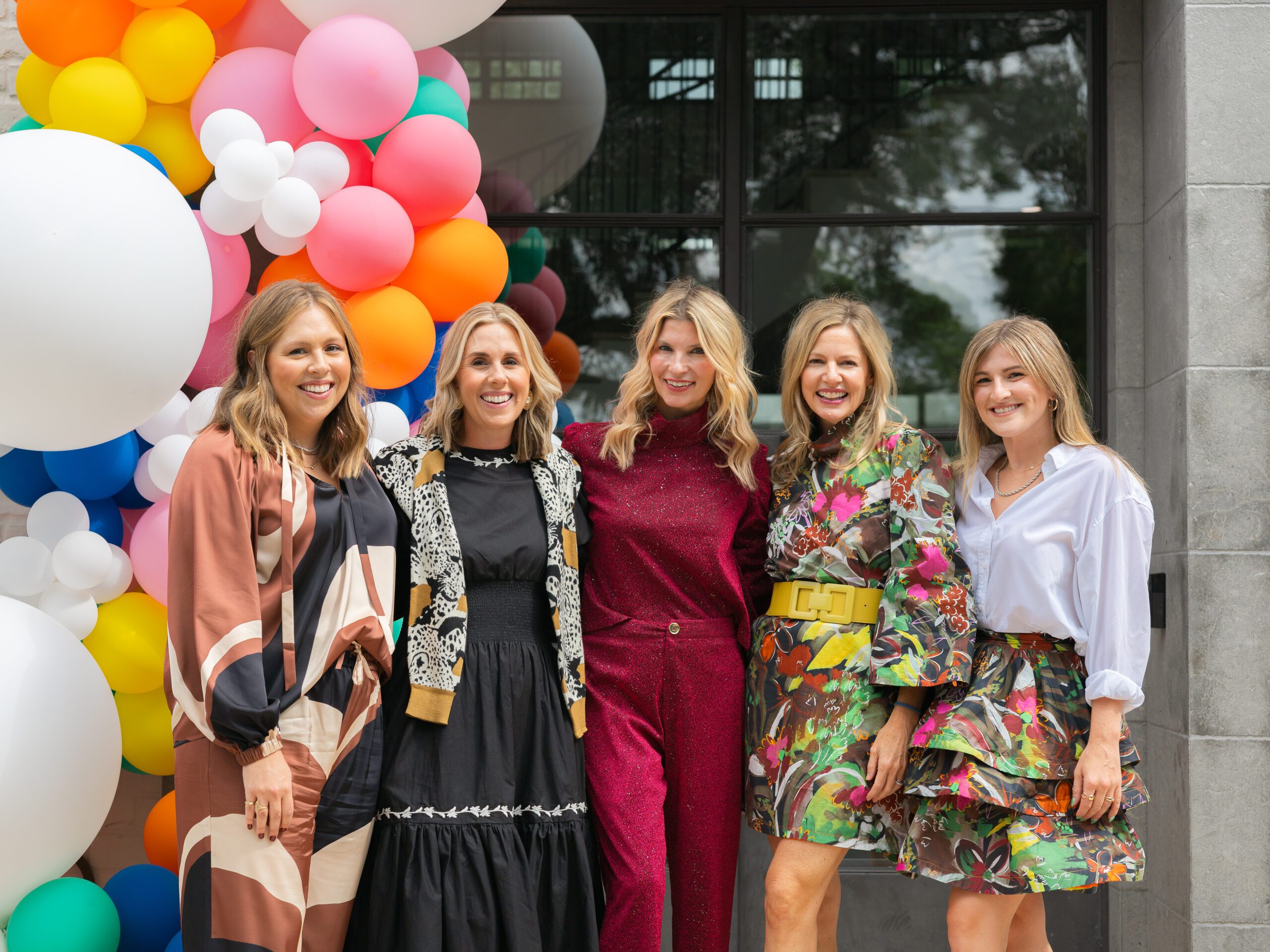 Group of designers posing at Dillard’s The Coterie Shop launch event with colorful balloon backdrop